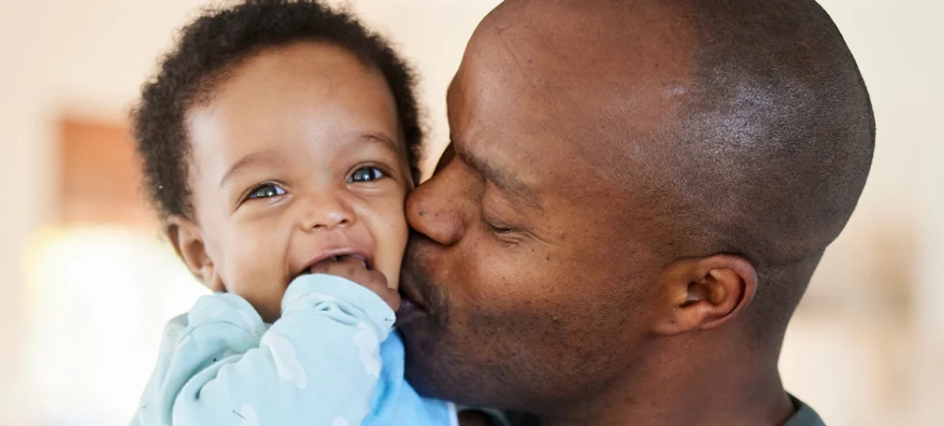 Father kissing his donor egg conceived baby.