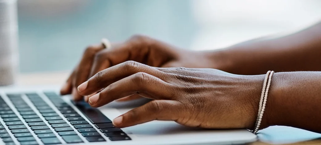 Hands typing egg donor blogs on a laptop.