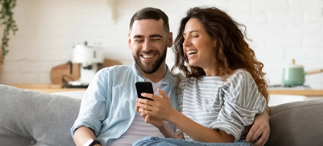 A smiling couple looking at the Fairfax EggBank egg donor database on their phone.
