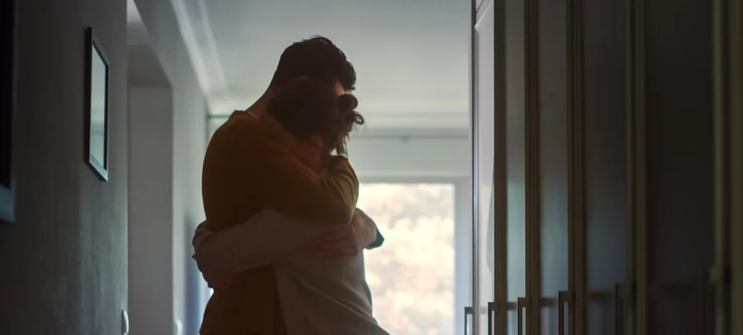 Couple hugging in hallway as they are sad because they suffer from infertility.