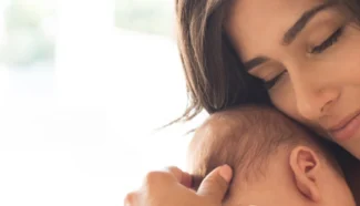New mother holding her donor egg conceived baby, happy she chose frozen donor eggs.
