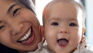 Egg donor recipient holding up her egg donor conceived baby, happy with her decision to use donor eggs.