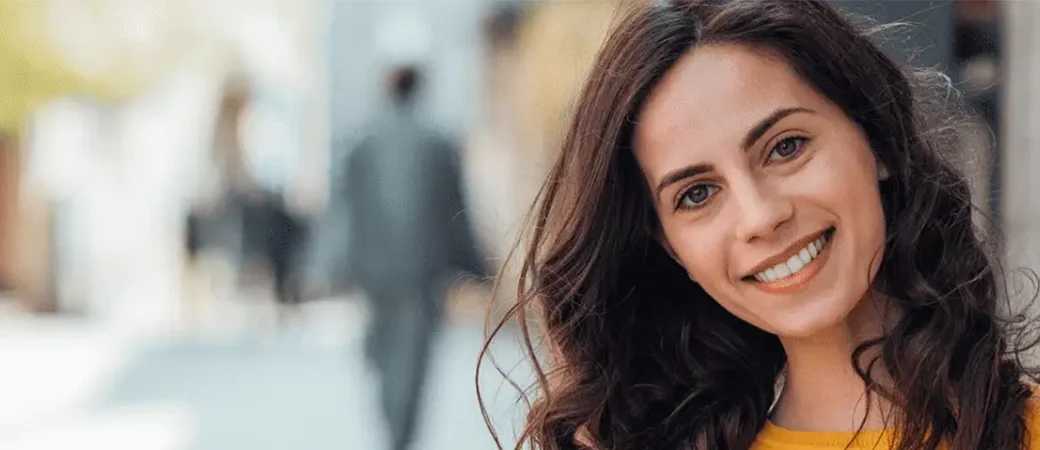 A brunette woman smiling because she knows she can have kids if she donates her eggs.