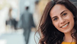 A brunette woman smiling because she knows she can have kids if she donates her eggs.