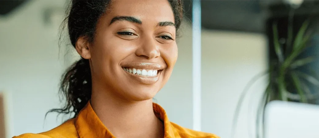 Woman smiling at her computer thinking about the pros of donating eggs.