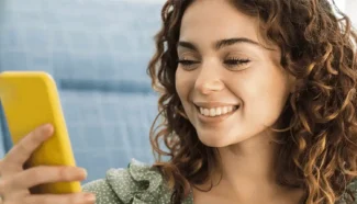 Egg donor smiling at phone as she reads the reasons she should donate eggs.