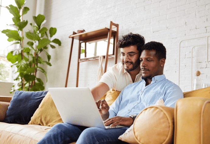 Male couple smiling at laptop computer while searching for their dream egg donor.
