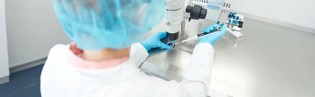 Embryologist working in a sterile IVF laboratory using a microscope